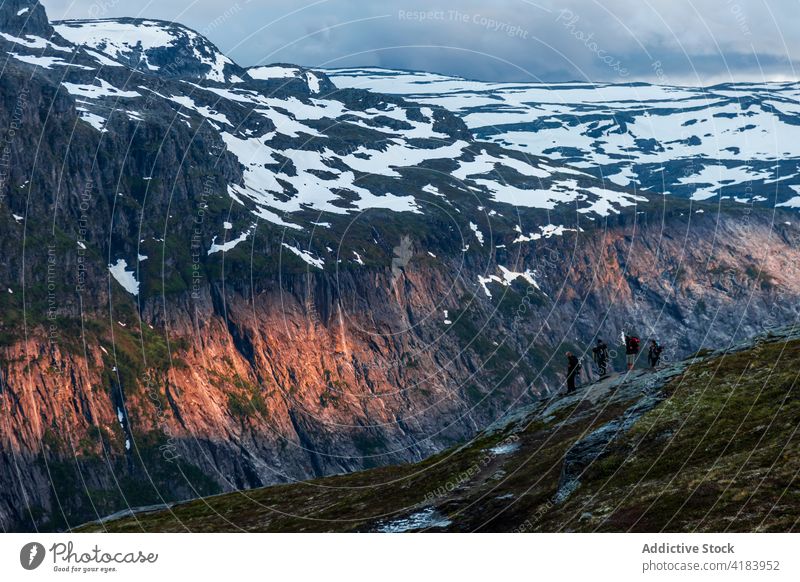Company of travelers on rocky hill in mountains group sunset hiker explore highland snow together norway adventure sunlight sundown evening rough landscape