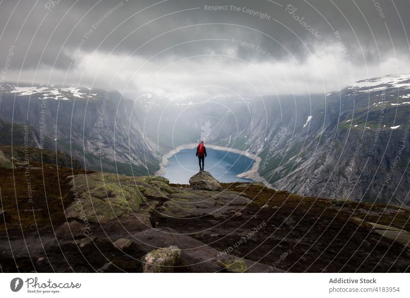Traveler standing on edge of rock in mountains traveler anonymous formation adventure backpack carefree freedom enjoy trolltunga norway vacation scenic stone