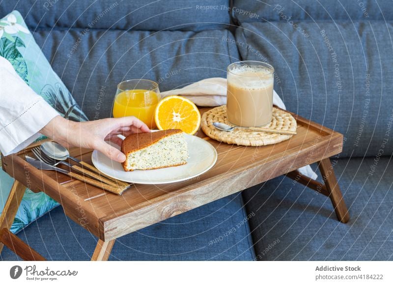 Crop woman with breakfast on tray at home cake biscuit dessert coffee juice morning female piece take slice cup homemade sponge baked bakery wooden beverage