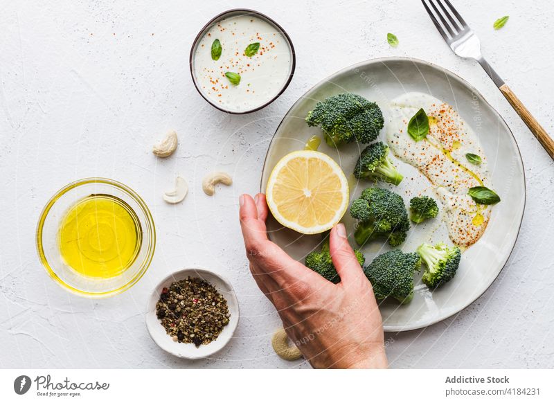Delicious broccoli with white sauce and lemon on plate healthy food menu vegetarian vitamin protein natural table cafe mix spice olive oil cashew nut cut slice