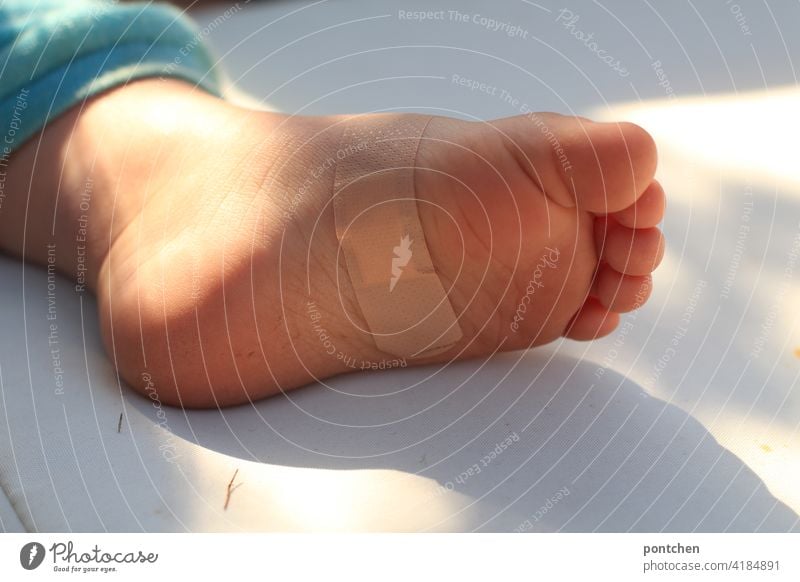 a foot with a band-aid is lying in the sun. Toddler injury and healing pavement violation consolation Healing Feet Protect Protection Considerate child-friendly