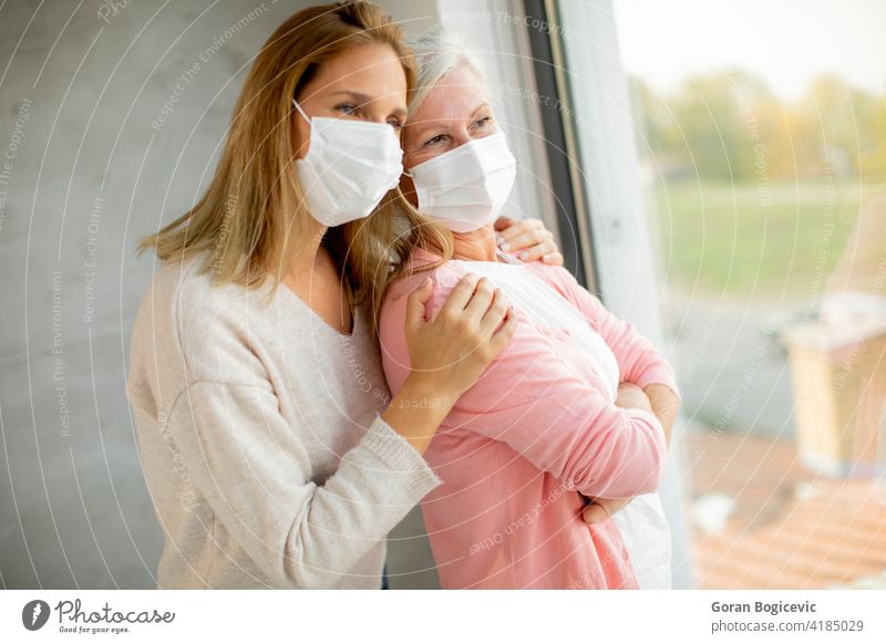 Senior woman with caring daughter at home wearing medical masks adult care caucasian corona coronavirus disease elder elderly epidemic family female fever flu