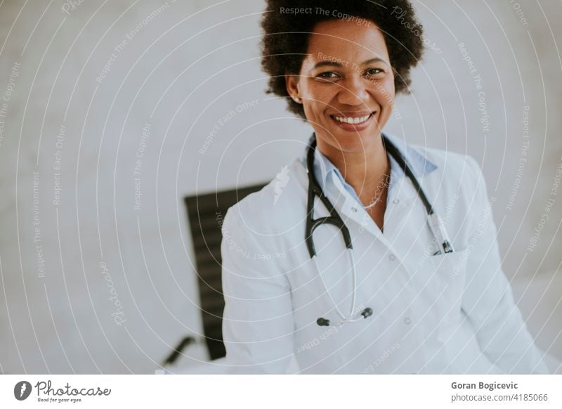 Female African American doctor wearing white coat with stethoscope standing by desk in office adult african american beautiful black clinic computer ethnic