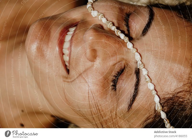 Calm happy woman lying on sandy seashore with seashells on face sunbath beach eyes closed bead relax peaceful holiday nature summer female young rest vacation