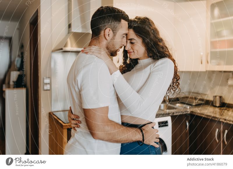 Tender couple embracing in kitchen embrace tender love home cuddle content weekend together young relationship happy affection enjoy casual glad stand cheerful