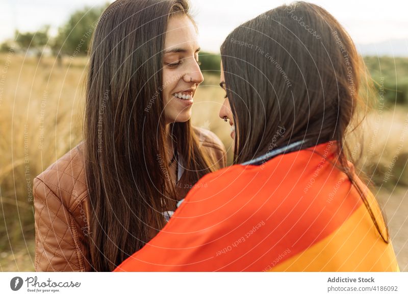 Lesbian couple with rainbow flag embracing in nature lesbian women hug wrap love lgbt female girlfriend gentle equal relationship homosexual unconventional