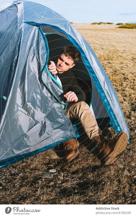Serious young guy relaxing in tent in camp during hiking trip man rest trekking traveler trendy serious nature wanderlust hike male style tourism vacation
