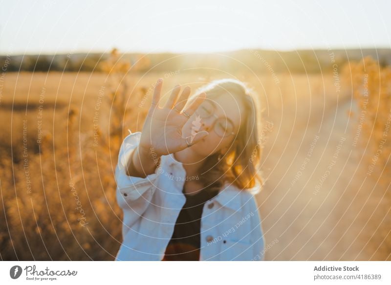 Stylish young woman showing hand in countryside in sunlight field five nature move confident style active holiday plant female trendy dry grass cloudless