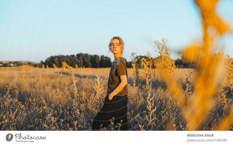 Dreamy young lady recreating in meadow on sunny day woman relax countryside confident traveler holiday feminine nature sunset enjoy field vacation female casual