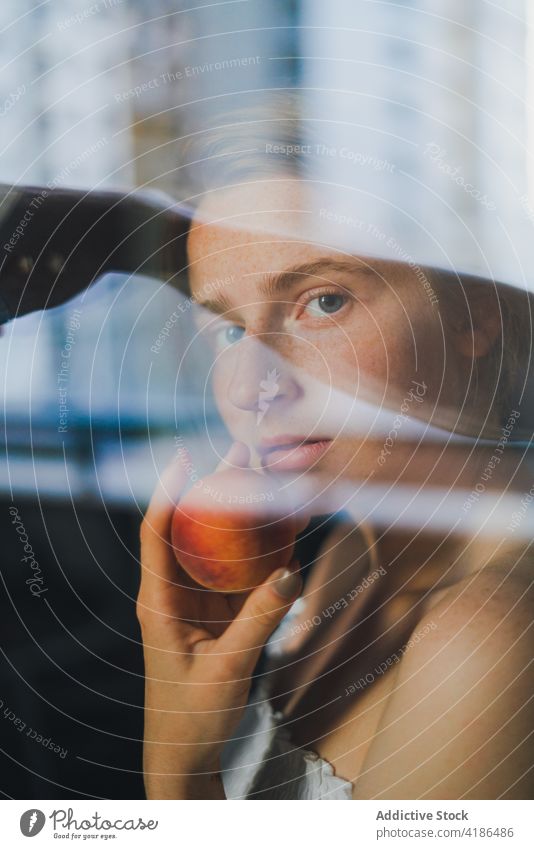Beautiful woman with peach through the glass dreamy reflection snack kitchen serene positive peaceful feminine counter tranquil charming bare shoulders