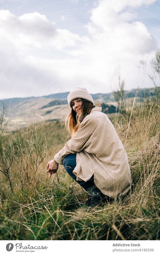 Smiling traveler on mountain under cloudy sky vacation nature highland smile grass woman enjoy trip content glad warm clothes sincere tourist idyllic spain
