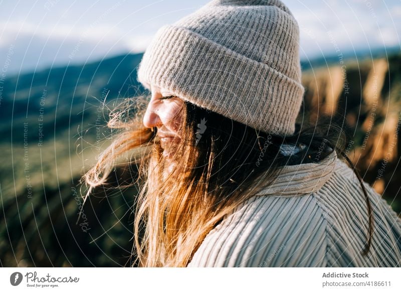 Smiling tourist in mountains on windy day smile eyes closed flying hair nature tourism highland enjoy woman traveler ridge vacation journey sky cloudy trip