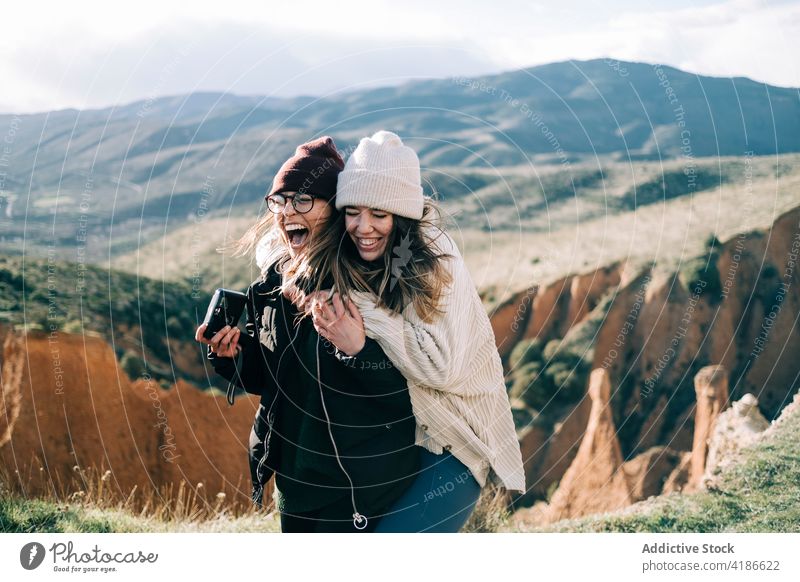 Happy girlfriends embracing against canyon and ridge during trip having fun mountain friendship embrace cheerful carefree tourism highland nature women