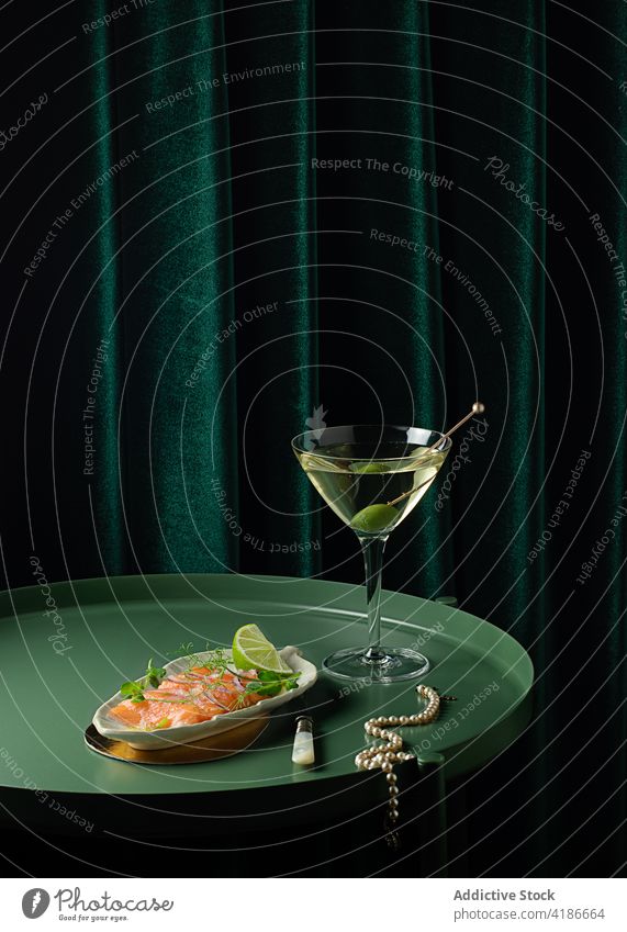 Classy necklace placed on table near delicious salmon snack and vermouth aperitif pearl knife alcohol elegant gastronomy palatable gourmet food cuisine olive