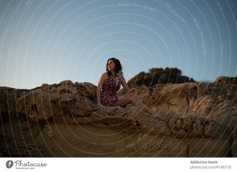 Woman dressed in a dress sitting on a rock on a summer day female woman nature beautiful stone beauty lifestyle happy fashion outdoor beach young sunset hair