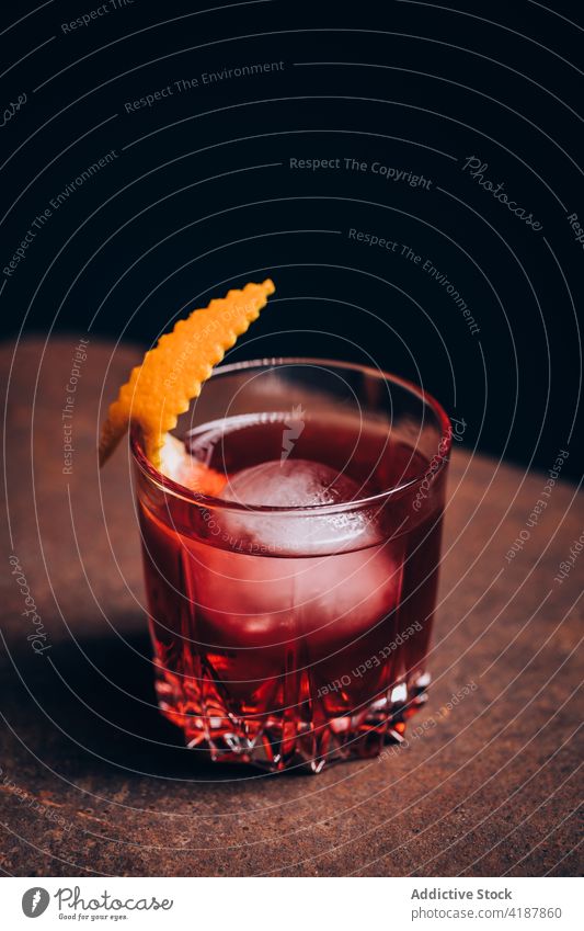 Glass of classic Negroni cocktail on sofa arm negroni alcohol refreshment drink beverage bitter blend gin vermouth ice mix orange peel garnish citrus cold