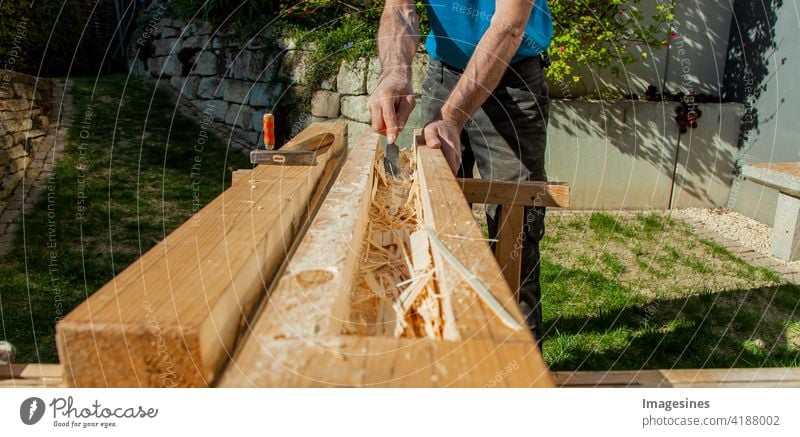 Woodwork. Hollowing out a hollow beam with chisels. Carpenter processes a wooden beam Milling Workshop on the outside Garden color picture Horizontal Bit
