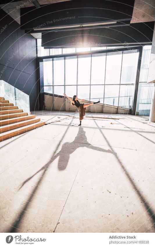 Anonymous dancer dancing in building during rehearsal artist choreography leg raised arm raised perform shadow theater woman prepare practice shade glass wall