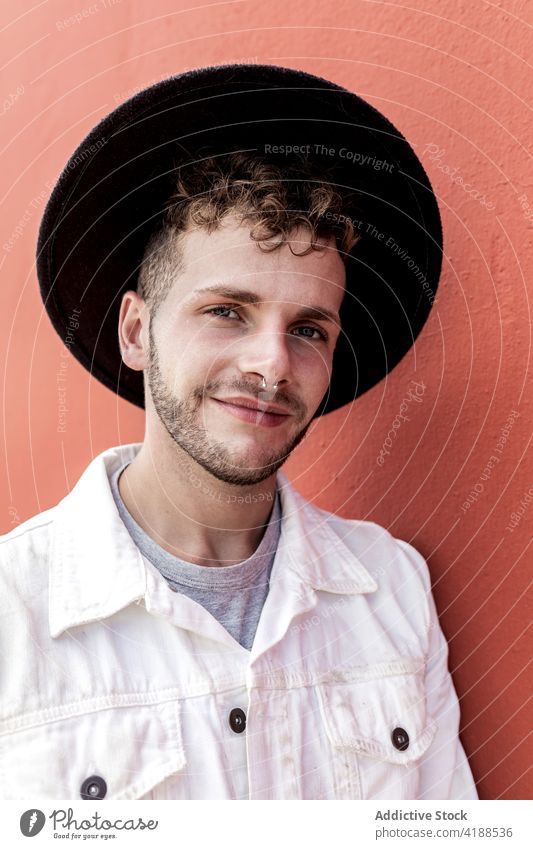 Happy young guy smiling against red background man smile confident content style trendy personality adjust hat relax street happy cool street style cheerful