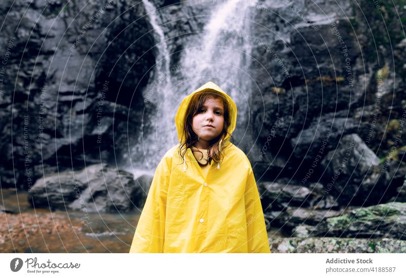 Girl in yellow raincoat against waterfall in mountains girl tourism highland nature wanderlust travel dreamy cascade fast flow bright energy dynamic teen