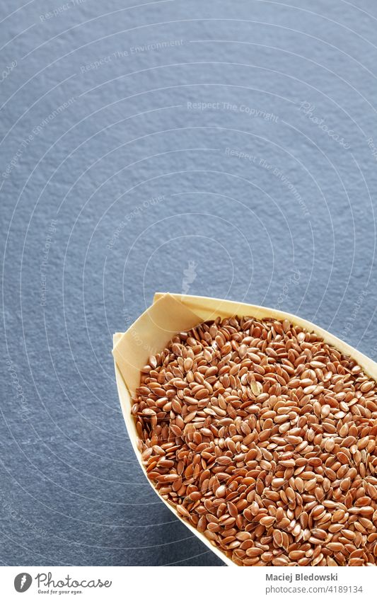 Brown linseeds in a natural wooden bowl on a slate background, space for text. flaxseed healthy brown copy space raw ingredient grain organic vegan nutrition
