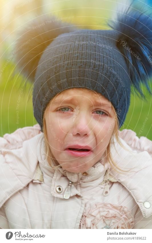 Sad crying offended girl cold autumn outdoor. Concept of upset child preschooler european desperation care cheerful hat hungry walking pom-pom lifestyle