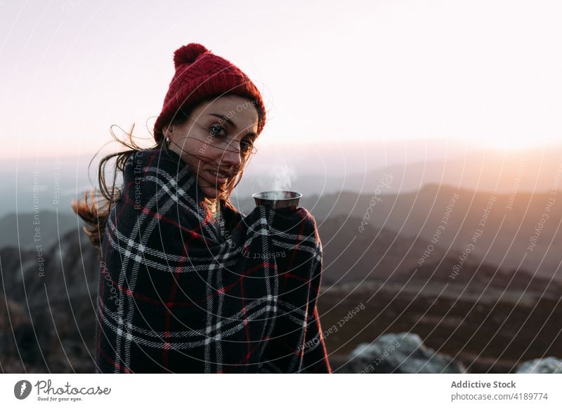 Traveler standing on rock in mountains traveler viewpoint observe highland hiker wool cap hot coffee beverage enjoy cup admire blanket explore amazing scenery