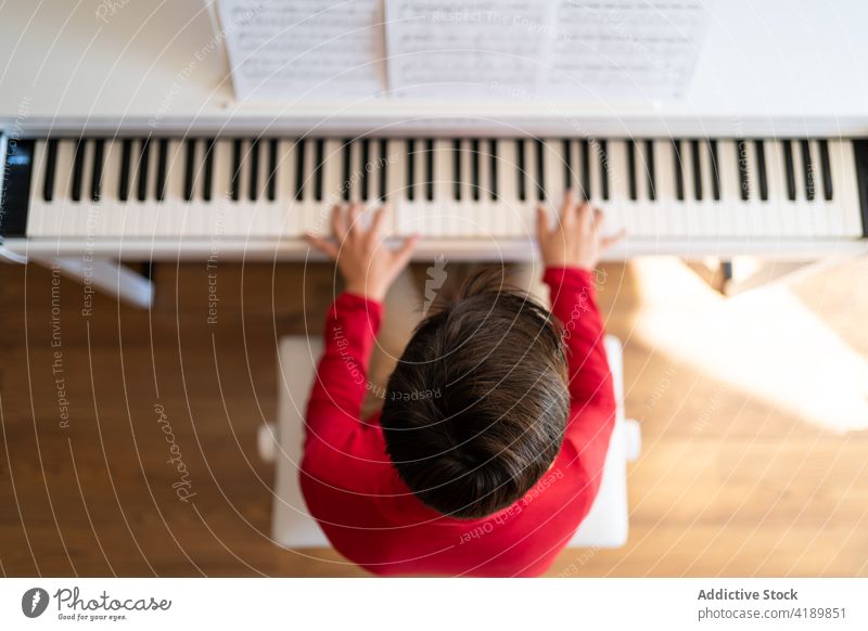 Boy playing piano at home child boy rehearsal song music musician note melody kid study sit talent instrument skill practice sound hobby pianist perform rhythm