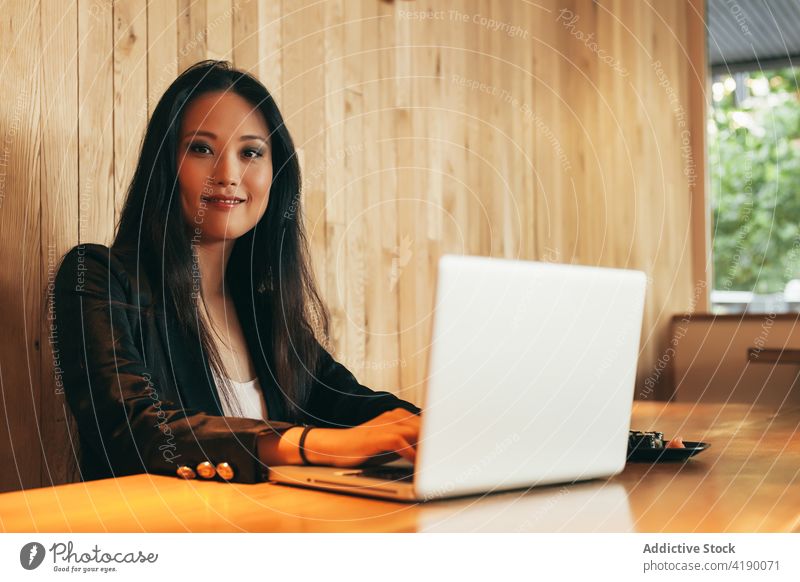 Ethnic businesswoman eating sushi and working on laptop in cafe roll project entrepreneur remote female asian ethnic table busy gadget computer using browsing