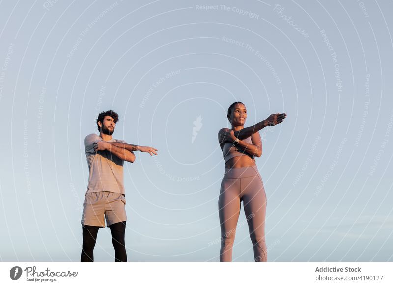 sportspeople stretching arms outdoors nature sky healthy lifestyle fit wellness woman together partner enjoy ripple sundown activewear athlete vitality twilight