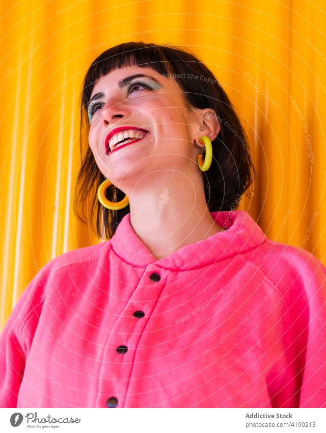 Positive woman in vibrant outfit in city vivid fancy cool urban fashion trendy cheerful female delight metal wall yellow smile red lips style enjoy glee