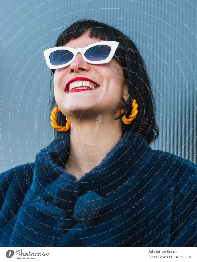 Stylish woman in trendy sunglasses in city fancy fashion vivid cool outfit urban delight female metal wall smile red lips style enjoy glee positive glad fur