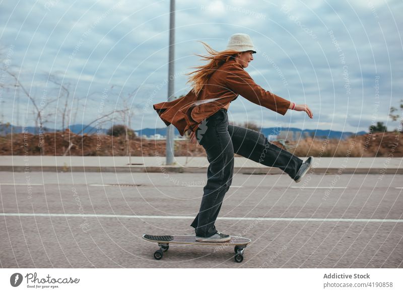 Active young lady riding skateboard in countryside woman ride longboard road activity trick hobby subculture practice active leg raised female trendy cool