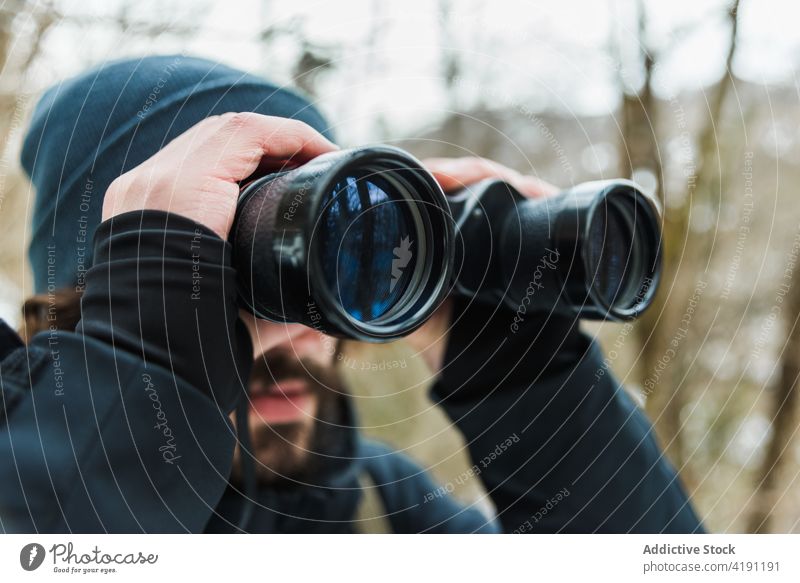 Traveling man looking in binoculars in winter forest traveler adventure hiker explore warm clothes male season snow nature woods vacation tourism cold frost