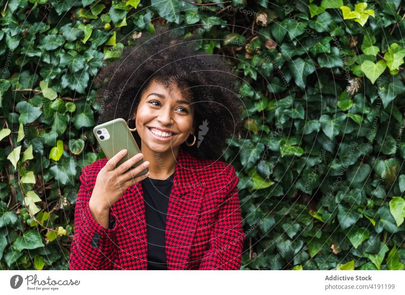 Smiling black woman talking on smartphone cheerful city female ethnic african american bench device gadget content smile using happy cellphone mobile optimist