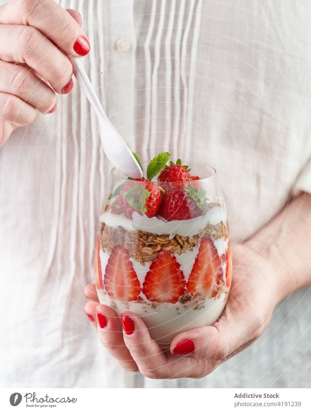 Crop woman with glass of delicious breakfast with fresh strawberries healthy food super food power bowl nutrient vitamin strawberry tasty transparent full