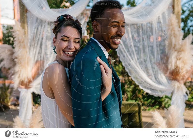 Cheerful newlywed couple hugging in garden cheerful bride groom wedding love together multiethnic multiracial diverse black african american embrace cuddle
