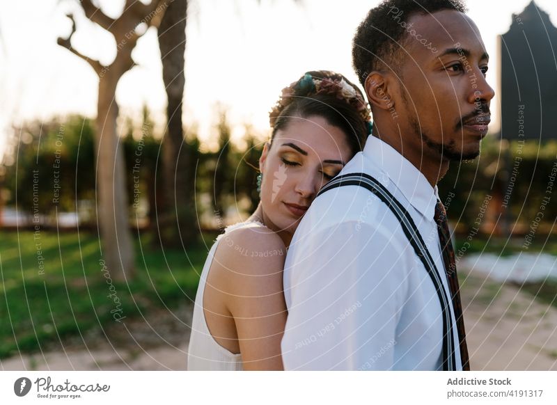 Cheerful newlywed couple hugging in garden bride groom wedding love together multiethnic multiracial diverse black african american embrace cuddle celebrate