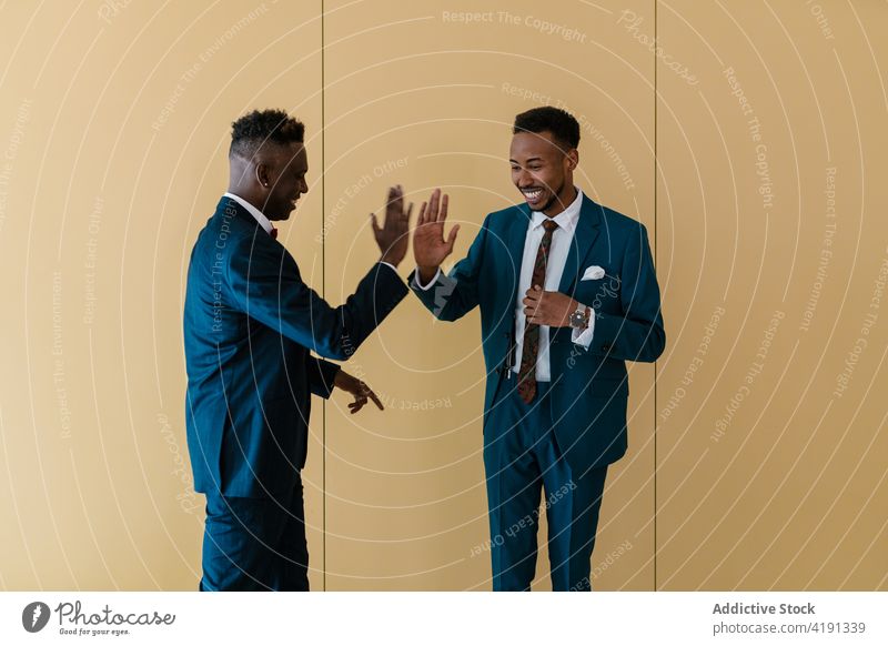 Cheerful groom and best man giving high five in room dance newlywed together carefree having fun wedding suit cheerful ethnic black african american male men
