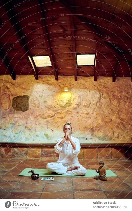 Mindful man meditating in Lotus pose on floor yoga lotus pose meditate eyes closed mudra statuette buddha spirit concentrate art sculpture buddhism religion