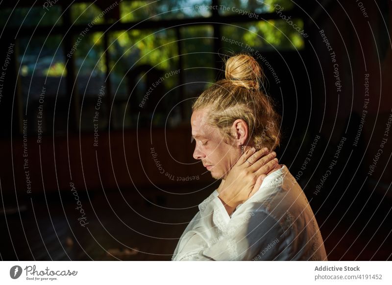 Dreamy man touching neck while practicing yoga in garden touch neck meditate practice eyes closed mindfulness wellbeing portrait profile concentrate