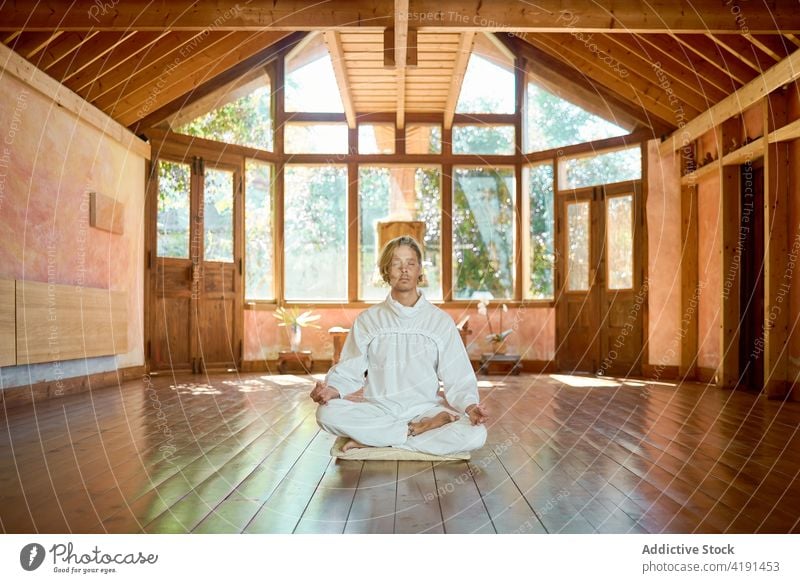 Man meditating in Lotus pose in room man meditate yoga lotus pose dhyana mudra harmony stress relief spirit floor stone culture quiet tradition barefoot stretch