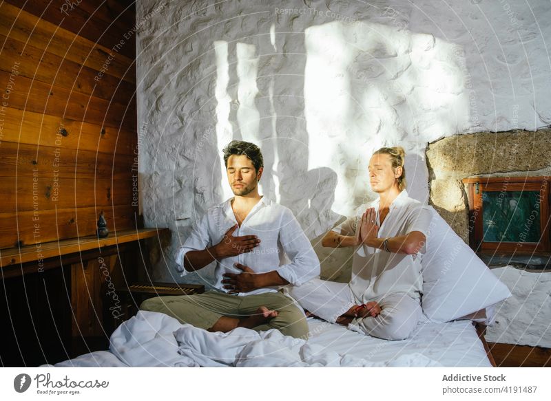 Two friends sitting on a bed while practicing meditation couple man blond bedroom yoga stretch flexibility wellness men health exercise sportswear people