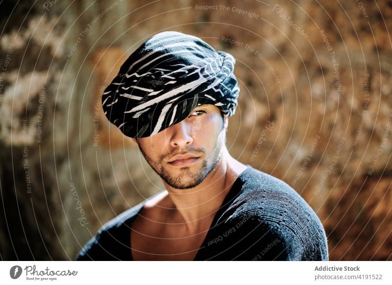 Hipster man in turban standing on the street model garment portrait confident outfit wear young ethnic male traditional building ethnicity arabic culture