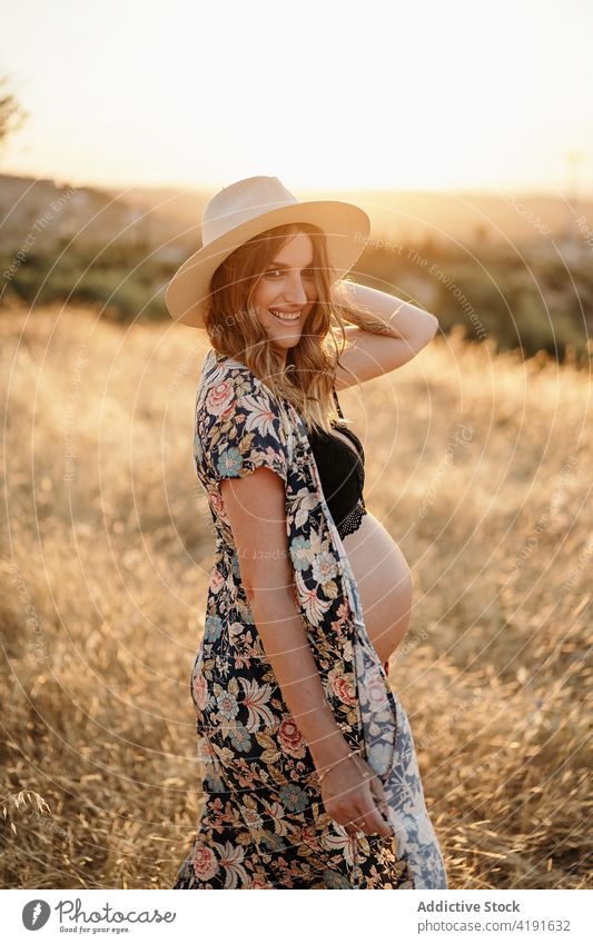 Pregnant female standing in field in countryside woman pregnant nature smiling maternal happy environment hat mother peaceful lingerie calm daytime expect