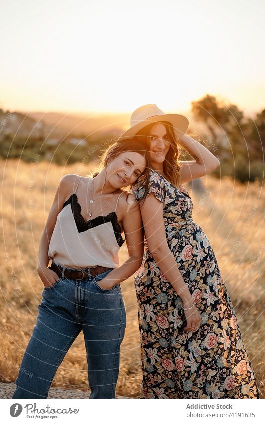 Cheerful friends in stylish outfit standing in field in sunny day women pregnant countryside nature positive charming cheerful sunlight female style maternal