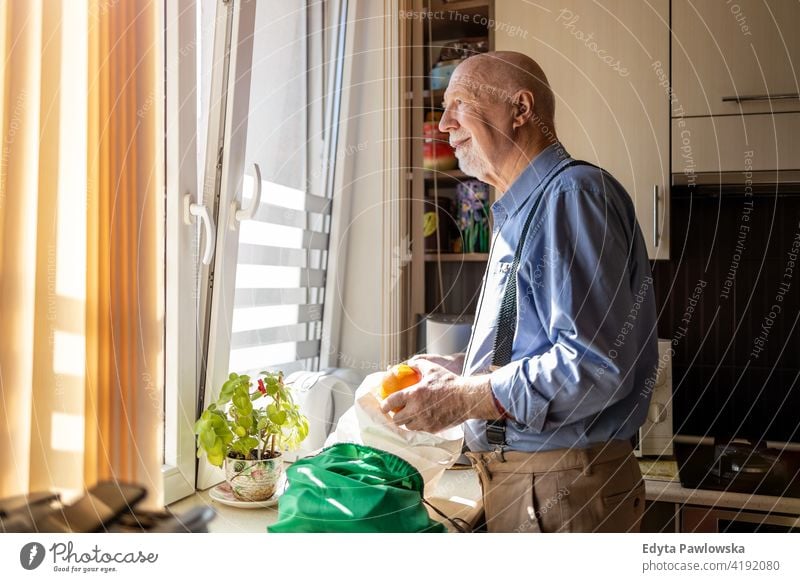 Senior Man Looking Through Window at Home real people candid genuine senior mature male man Caucasian elderly home house old aging domestic life grandfather