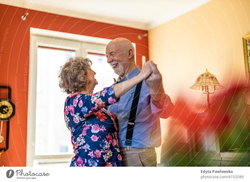 Happy senior couple dancing together at home real people candid genuine woman mature female love bonding Caucasian elderly house old aging domestic life
