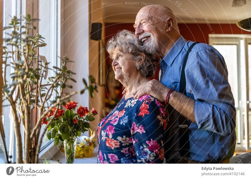 Senior Couple Looking Through Window real people candid genuine woman senior mature female couple together love bonding Caucasian elderly home house old aging