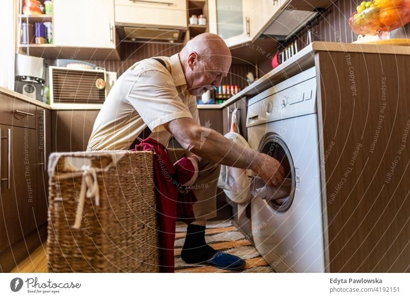 Senior man doing the laundry at home real people candid genuine senior mature male Caucasian elderly house old aging domestic life grandfather pensioner